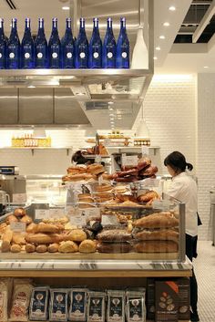 a woman standing in front of a counter filled with donuts