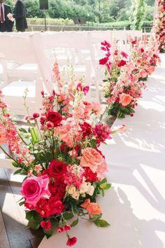 a row of white chairs with red and pink flowers on them