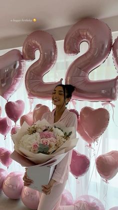 a woman holding a bouquet of flowers and balloons with the number twenty two on it