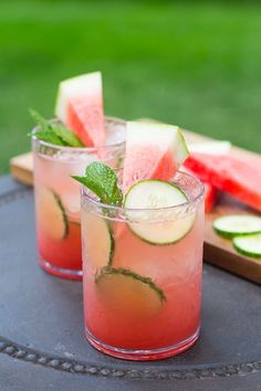 two glasses filled with watermelon and cucumber on top of a table