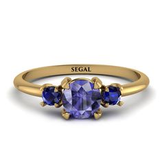 three stone ring in yellow gold with an oval blue sapphire and the word segel on it