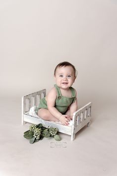 a smiling baby sitting in a white crib