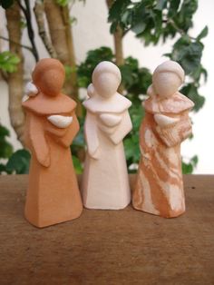 three small figurines sitting on top of a wooden table