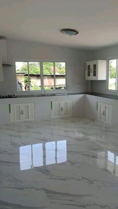 an empty kitchen with white cabinets and marble flooring is pictured in this image from the inside