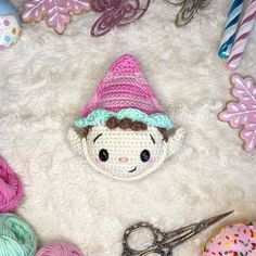 there is a crocheted doll with a hat and scissors on the floor next to some yarn