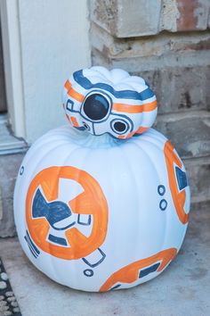 a star wars pumpkin sitting on top of a white pumpkin shaped like a bbg helmet