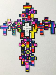 a cross made out of colorful pieces of paper with words written on the front and back