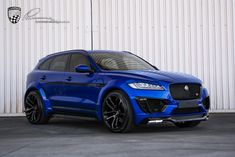 a blue suv parked in front of a white wall with black rims on it