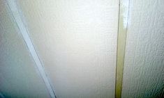 the corner of a room with white walls and a yellow line on the wall next to it