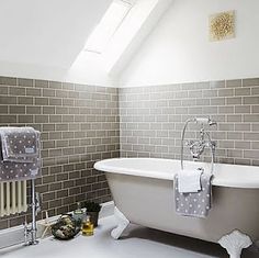 a white bath tub sitting under a window next to a radiator and towel rack