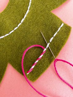 a green piece of felt with white stitching on it and a pair of scissors