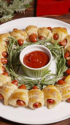 a white plate topped with pigs in a blanket next to a bowl of ketchup