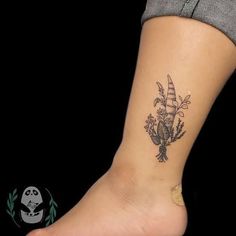 a woman's foot with a small tattoo on the side of her leg and flowers