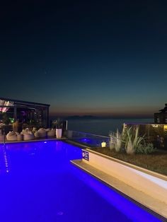 an outdoor swimming pool at night with blue lighting