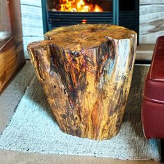 a wooden table sitting in front of a fire place next to a red leather chair