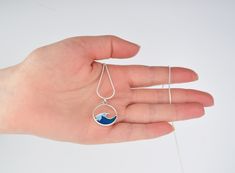 Looking for the perfect accessory to showcase your love for the ocean? Look no further than our handmade silver wave resin necklace. Our jewelry is crafted by the talented artist at Schafer Art Studio in Oregon, ensuring that each piece is not only beautiful but also one-of-a-kind. This charm is a dainty.9 inch, adding a touch of femininity and elegance to this piece Our jewelry is the perfect gift for any woman, teen girl, surfer or sea lover in your life. Whether you're shopping for a birthday Ocean-inspired Pendant Necklace, Ocean Resin Pendant, Ocean-inspired Silver Resin Necklace, Ocean-inspired Glass Necklaces For Gifts, Blue Resin Ocean-inspired Necklaces, Sophisticated Jewelry, Sea Lover, Beautiful Ocean, Resin Necklace