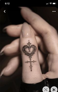 a person with a tattoo on their wrist holding up a cross and heart shaped key