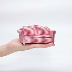 a hand holding a red and white striped couch