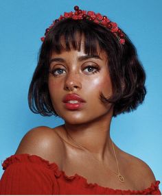 a woman wearing a red dress with a flower crown on her head, against a blue background