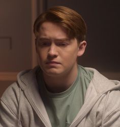 the young man is looking down at his cell phone while sitting in front of him