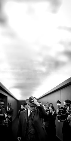 a man in a suit and tie walking down a hallway with other people behind him