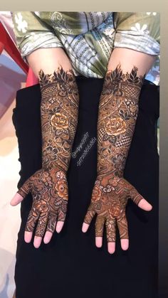 two hands with henna tattoos on them, one is showing off the intricate design