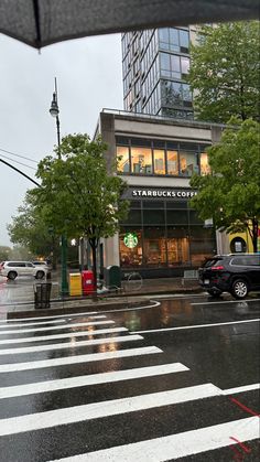 an umbrella is open on a rainy day in front of starbuckss and coffee shops