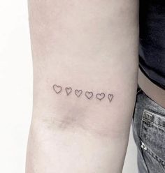 a woman's arm with four small hearts on the left side of her arm