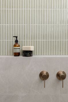 two soap dispensers on the side of a tiled wall