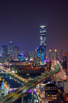 an aerial view of a city at night with lights on and bridges in the foreground