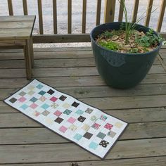 a potted plant sitting on top of a wooden deck next to a patchwork quilt