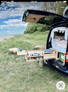 an open trunk in the back of a van with its bed pulled up to it