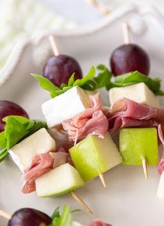 appetizers are arranged on skewers with grapes and cheese