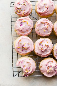 a cooling rack filled with pink frosted cupcakes