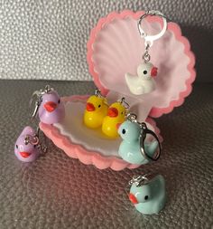 three rubber ducks are sitting on a tray with keychains in the shape of seashells