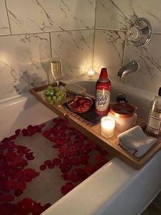 a bath tub filled with lots of different types of food and drinks next to candles