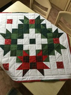 a quilted table topper sitting on top of a dining room table with chairs