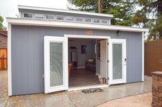 a dog is standing in the doorway of a small shed with its front door open