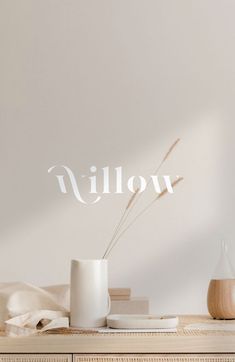 a white vase sitting on top of a wooden table next to a book and cup