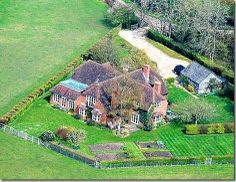 an aerial view of a large house in the middle of a lush green field with lots of trees