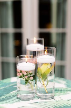 three candles with flowers in them sitting on a table