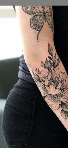 a woman's arm with flowers and butterflies tattoo on her left arm, while the rest of her leg is black