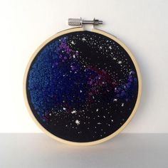 an embroidery project with blue, purple and white stars in the sky on a black background