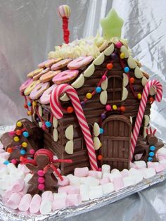 a large gingerbread house with candy and candies on the roof is shown in tin foil