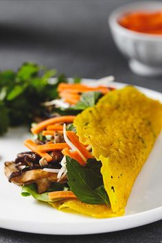 a white plate topped with a tortilla covered in veggies