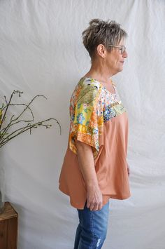 The Floral Pattern Top with Apricot Bottom is a stylish and chic curvy short sleeve top that is perfect for any casual or semi-formal occasion. The top features a beautiful floral pattern on the top half in shades of blue, green, and white. The bottom half is a solid apricot color, adding a pop of color to the overall look. The short sleeves provide a comfortable and casual fit, making it perfect for everyday wear. The curvy fit is designed to fit and flatter a variety of body types. The top is Casual Floral Print Half Sleeve Tops, Summer Floral Print Half Sleeve Tops, Casual Half Sleeve Tops With Floral Print, Casual Half Sleeve Floral Print Tops, Relaxed Fit Floral Print Half Sleeve Tops, Relaxed Fit Half Sleeve Floral Print Tops, Relaxed Fit Half Sleeve Floral Tops, Floral Print Half Sleeve Relaxed Fit Tops, Cotton Floral Print Half Sleeve Tops