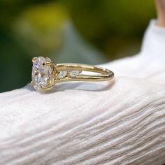 a woman's hand holding a yellow gold ring with a white diamond on it