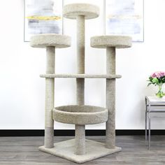 a cat tree in the middle of a room with two pictures on the wall behind it