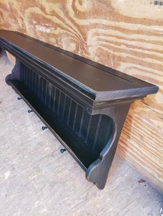 a black shelf sitting on top of a wooden floor next to a piece of wood