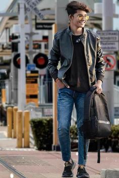 a young man is walking down the street with his hand in his pocket and wearing sunglasses